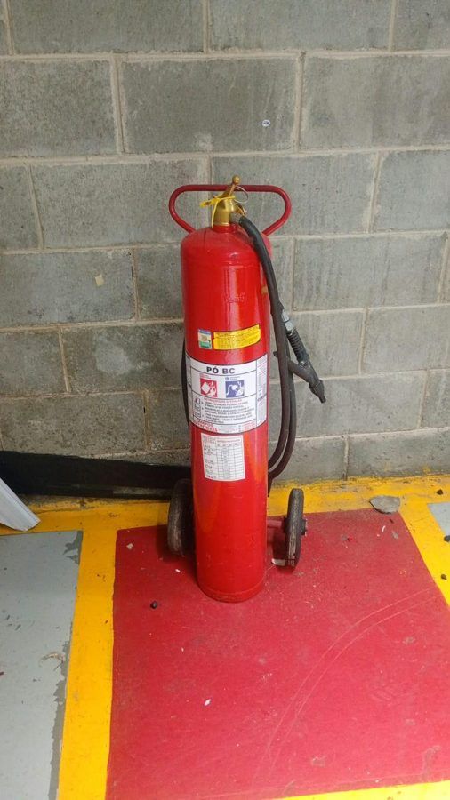 Extintor em manutenção na oficina e extintor sobre rodas em piso demarcado