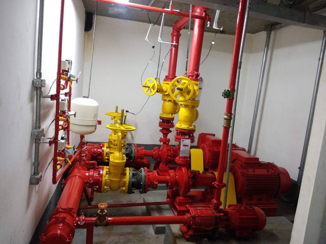 Casa de bombas com bombas elétricas pintadas de vermelho e válvulas de bloqueio amarelas