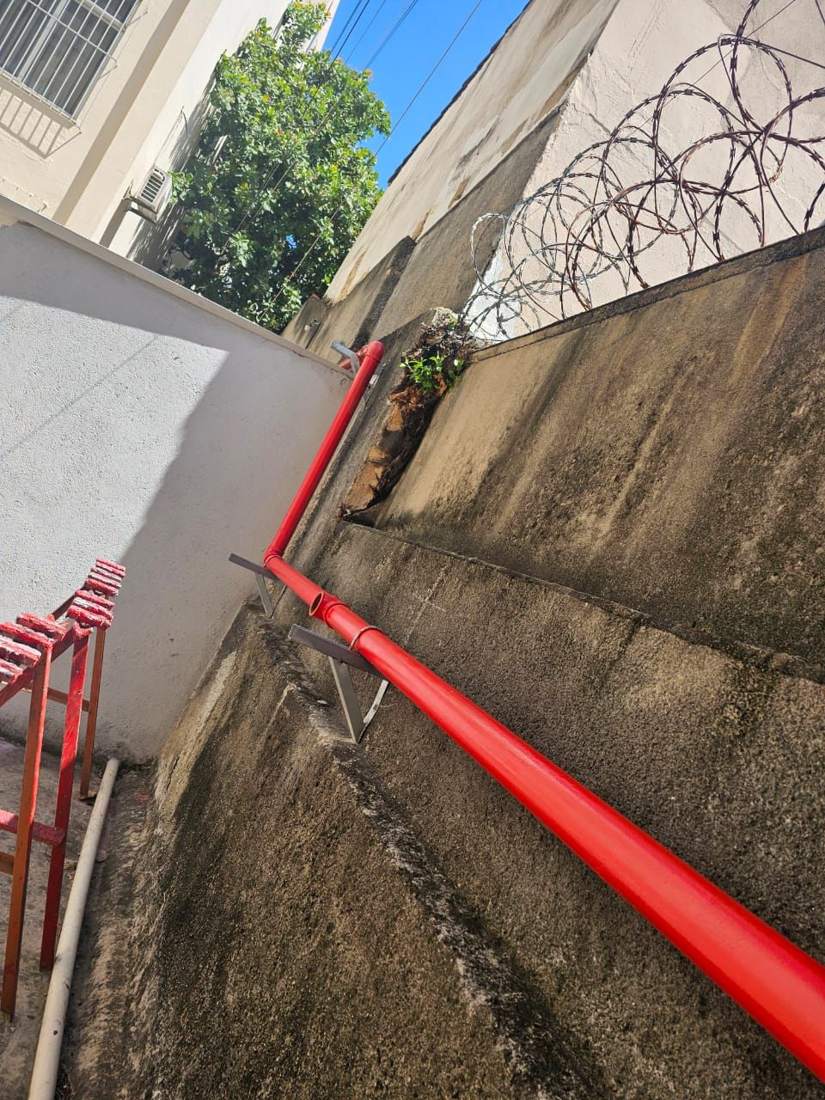 Rede de incêndio aérea pintada de vermelho ao longo de muro